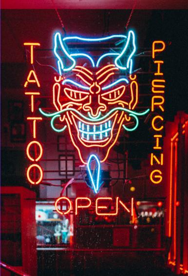 Letrero de tienda de tatuajes y piercings en neon luminoso